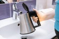 A woman pours water into a kettle in a hotel sink Royalty Free Stock Photo