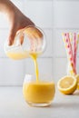 A woman pours a yellow smoothie into a glass. Detox, healthy eating.