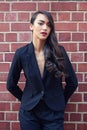 Woman, power suit and chic fashion with hair on brick wall background, confidence and pride with makeup. Glamour