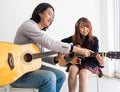 Woman practice while sitting on a chair. The teacher`s hand-touching strings explain cords, the basics of playing the guitar, the