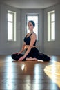 A woman practices yoga in a fitness room at dawn. Concentration, beautiful sunshine, stretching, healthy lifestyle.