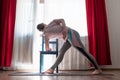 Woman practices yoga doing Extended Triangle Pose or Trikonasana using chair Royalty Free Stock Photo