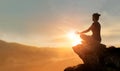 Woman practices yoga and meditating on the mountain sunset background