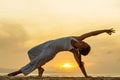 Woman practices yoga at the seashore at sunset on Bali in indonesia