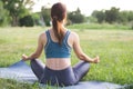 The woman practices yoga and sits in the lotus position with her back to the camera. Beautiful young woman meditates in the park. Royalty Free Stock Photo