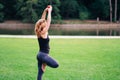 A woman practicing drunk yoga outdoor at the park. Woman holding a glass of alcohol doing pilates Royalty Free Stock Photo