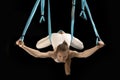 Woman practicing fly yoga using hammock suspended from the ceiling. Girl gymnast in trapeze class. Black background