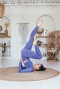 Woman practicing at home does a shoulderstand with her legs up