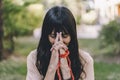 Woman practicing meditation sitting in yoga asana Kali Mudra holding a japa mala outdoors.