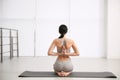 Woman practicing seiza asana in yoga studio, back view. Vajrasana pose