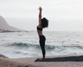 Woman practicing Urdhva Hastasana pose by ocean. Slim female standing outdoors in Raised Hands Pose