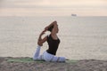 Woman practicing yoga on the beach. One legged King pigeon pose, Eka Pada Pajakapotasana. Outdoors sports. Healthy living