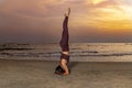 Woman practicing yoga on the beach at sunset.