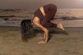 Woman practicing yoga on the beach at sunset.