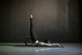 Woman practicing yoga, doing Salabhasana pose with wheel.