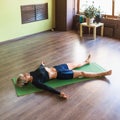 Woman practicing yoga, doing shavasana exercise with pranayama breathing practice, relaxing asana, lying on a mat in the room Royalty Free Stock Photo