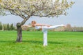 Woman is practicing yoga, doing Virabhadrasana III exercise, standing in Warrior three pose near tree Royalty Free Stock Photo