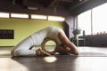 A woman practicing yoga, exercises the muscles of the spine on a wooden circle, lies on a mat in the studio Royalty Free Stock Photo