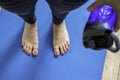 Woman practicing yoga, holding a bottle water. Feet with pink pedicure of woman on blue mat Royalty Free Stock Photo