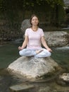 Woman is practicing yoga in lotus pose at mountain warefall lake Royalty Free Stock Photo