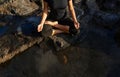 Woman practicing yoga and meditation in lotus position on black stones near the sea