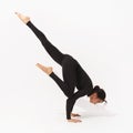 Woman practicing yoga, performs the exercise Eka Pada Bakasana, crane pose with outstretched leg