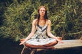 Woman practicing yoga on pier by river.