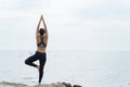 A woman practicing yoga postures on the beach.