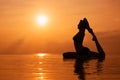 Woman practicing yoga, silhouette on the beach at sunset Royalty Free Stock Photo