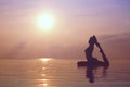 Woman practicing yoga, silhouette on the beach at sunset Royalty Free Stock Photo