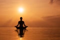 Woman practicing yoga, silhouette on the beach at sunset