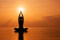 Woman practicing yoga, silhouette on the beach at sunset