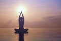 Woman practicing yoga, silhouette on the beach at sunset