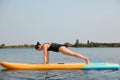 Woman practicing yoga on SUP board on river Royalty Free Stock Photo