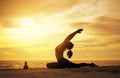 woman practicing yoga during surrealistic sunset at the seaside.