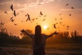 Woman praying and free the birds to nature on sunset background AI generated Royalty Free Stock Photo