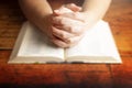 Woman Praying with Her Hands Folded over Her Bible Royalty Free Stock Photo