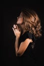 Woman prays on a black background