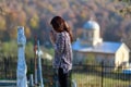 woman prays in front of a cross in the cemeter