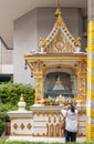 A woman prays with her hands on her hair in a small temple on the sides of a busy road in Bangkok, Thailand Royalty Free Stock Photo
