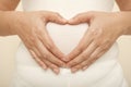 Woman pregnant do hand heart at paunch