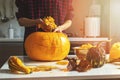 Woman prepare pumpkin for halloween holiday decoration remove seeds at home kitchen Royalty Free Stock Photo