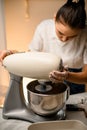 Woman prepares dough using modern electric kitchen stand mixer.