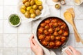 Woman prepares a family dinner. Top view of meatballs in tomato sauce in a cast iron pan, baked potatoes with herbs Royalty Free Stock Photo