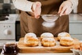 Woman prepares fresh donuts with jam in home kitchen. Cooking traditional Jewish Hanukkah sufganiyot.