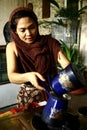 A woman prepares hot cocoa drink manually from freshly ground cocoa beans.