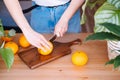 Woman cutting oranges in a kitchen full of plants. Royalty Free Stock Photo