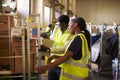 Woman prepares roll cage for delivery, checked by supervisor