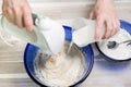 Woman prepares a waffle dough with a stirrer.