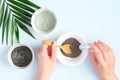 Woman preparing cosmetic clay on pastel blue background. Natural organic SPA facial mask. Flat lay, top view. Face skin care and